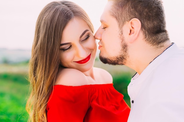 Closeup ritratto di una coppia uomo baciare donna sulla sua guancia sorridente Giovane coppia di uomo e donna all'aperto