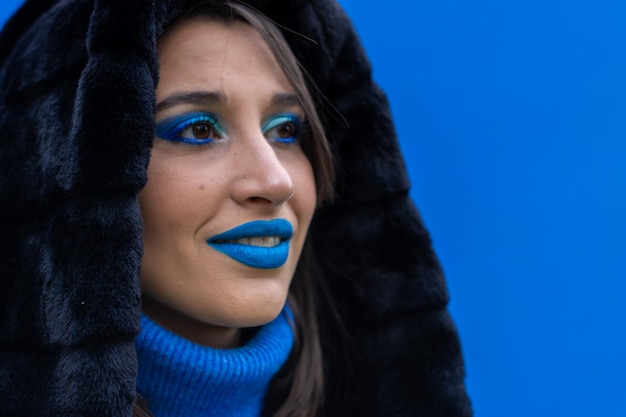 Closeup ritratto di una giovane donna con il trucco blu su sfondo blu