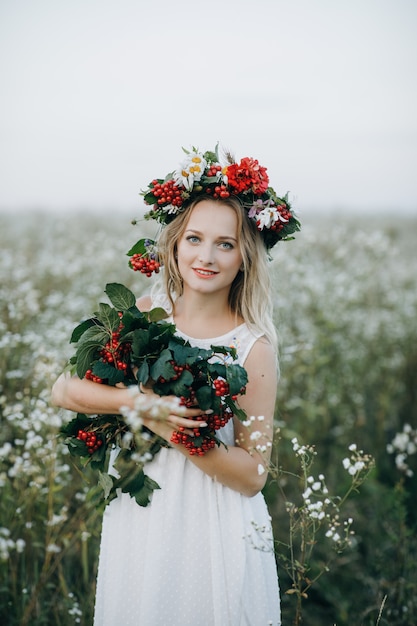 Closeup Ritratto di una ragazza bionda con gli occhi azzurri con una corona di fiori in testa