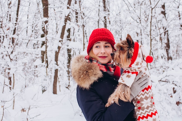 Closeup ritratto di una ragazza con un cane nella foresta invernale, ragazza con un cappello a maglia rosso