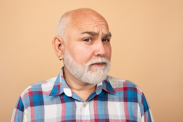 Closeup ritratto emotivo di un vecchio uomo anziano maturo con barba grigia isolato su sfondo studio