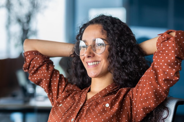 Closeup ritratto fotografico di una giovane donna latinoamericana di successo felice che è seduta in ufficio