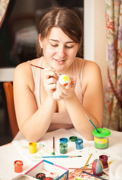 Closeup ritratto ragazza bruna pittura uovo di Pasqua a casa