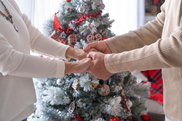 Closeup senior donna e uomo per mano sentimento sincero amore supporto assistenza assistenza Un albero di Natale decorato sullo sfondo Persone età famiglia cura e concetto di supporto