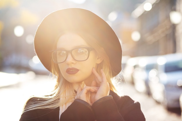 Closeup street ritratto di donna bionda alla moda con le labbra rosse con gli occhiali e cappello. Spazio per il testo