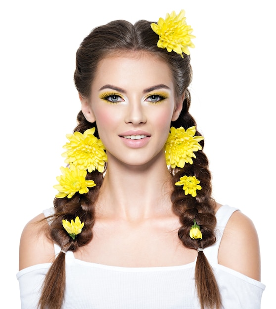 Closeup volto di una giovane bella donna sorridente con trucco giallo brillante Moda ritratto Ragazza attraente con trecce acconciatura alla moda isolata on white Trucco professionale