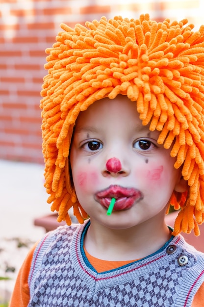 Clown bambino che mangia lecca-lecca in una festa