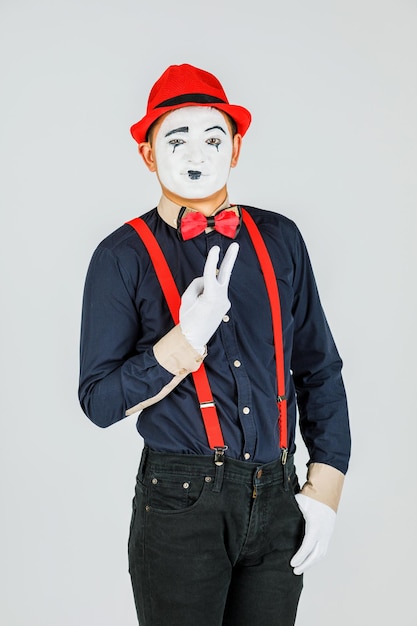 Clown con bretelle rosse e cappello rosso su sfondo bianco