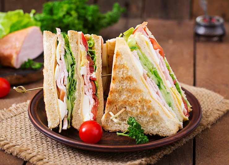 Foto club sandwich con formaggio, cetriolo, pomodoro, prosciutto e uova.