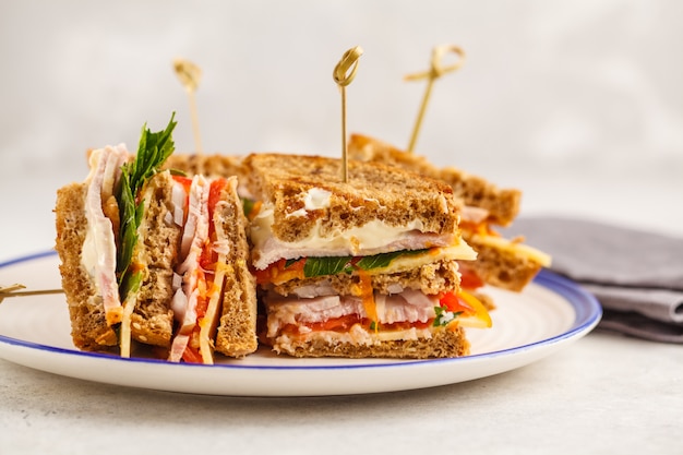 Club sandwich di prosciutto, verdure e formaggio su un bianco