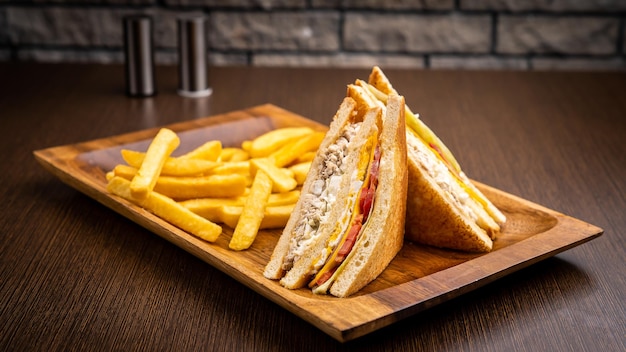 Club sandwich e patatine fritte isolate su tavola di legno vista laterale sul tavolo fast food