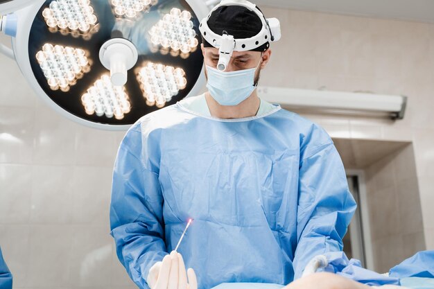 Coagulazione laser endovenosa per il trattamento delle vene varicose Il chirurgo vascolare tiene EVLT Fibra ottica laser rossa per il trattamento della tromboflebite trombosi delle gambe in sala operatoria