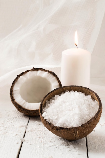 Cocco e prodotti termali: sale marino, olio di cocco, aroma di cocco con candela su sfondo bianco. Messa a fuoco selettiva