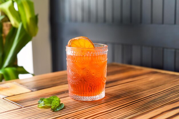 Cocktail alcolico Aperol Spritz con fetta d'arancia su tavolo di legno contro parete scura con copia spac