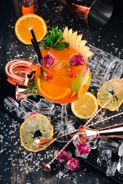 Cocktail alcolico Aperol Spritz con rose su fondo di legno nero