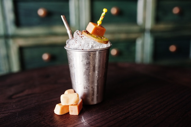 Cocktail alcolico con dolci e caramelle nel piccolo secchio d'argento al tavolo del bar