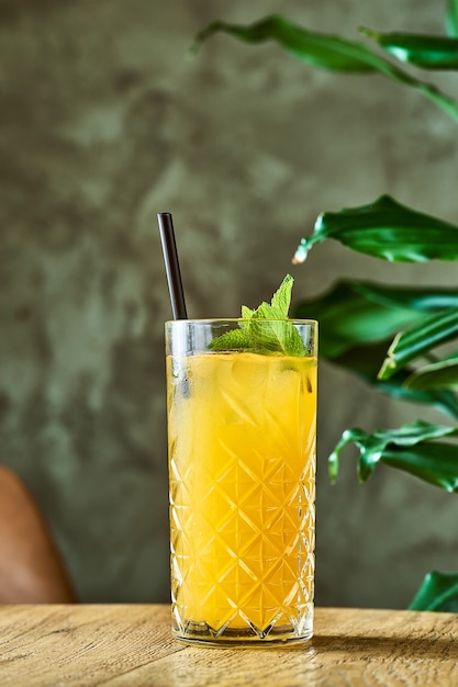 Cocktail alcolico con succo d'arancia, lime e menta in un bicchiere con ghiaccio