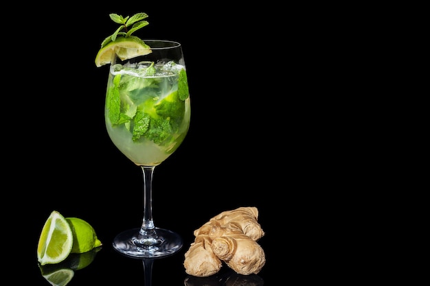 Cocktail alcolico con zenzero lime e menta su fondo nero