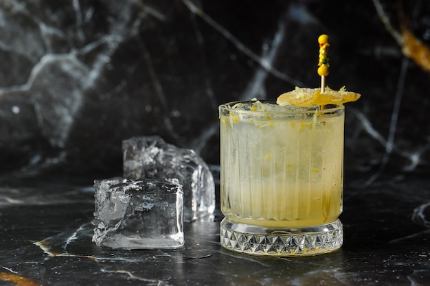 Cocktail alcolico della bevanda della penicillina del whisky scozzese con lo sciroppo del miele del limone e il bicchiere da cocktail dello zenzero candito su fondo nero