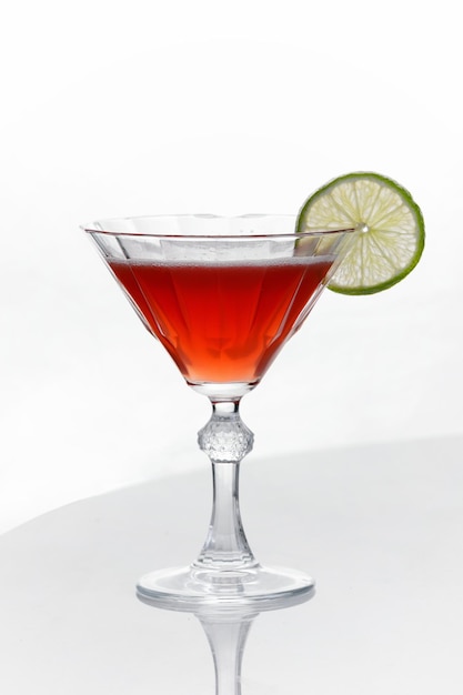 Cocktail alcolico di colore rosso con una fetta di lime in un bicchiere da cocktail