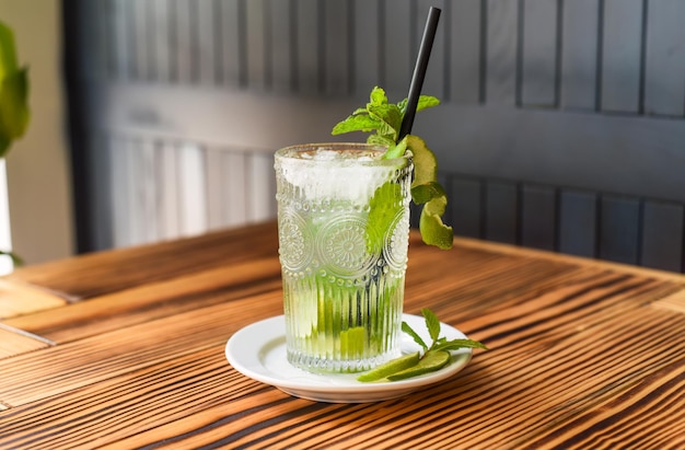 Cocktail alcolico Mojito su tavolo di legno contro parete scura con spazio copia