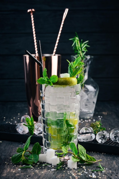 Cocktail alcolico Mojito su uno sfondo di legno nero