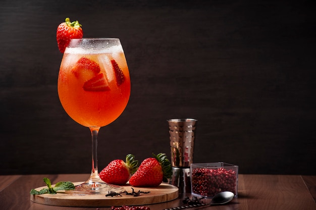 Cocktail alla fragola su un vassoio di legno, fragole intere e distributore di vodka