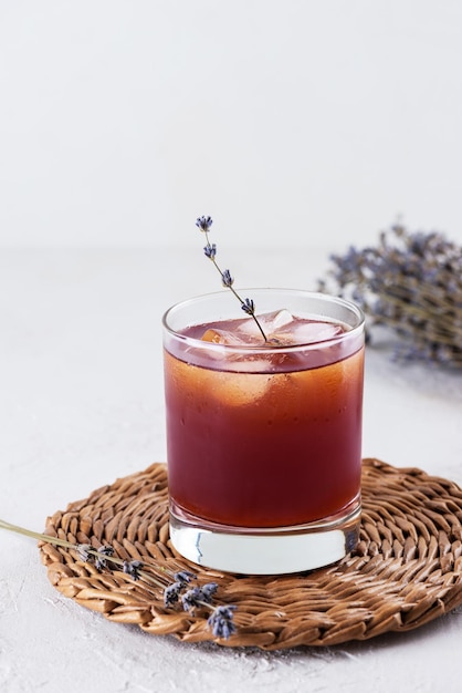 Cocktail analcolico con ghiaccio e lavanda su un tavolo bianco