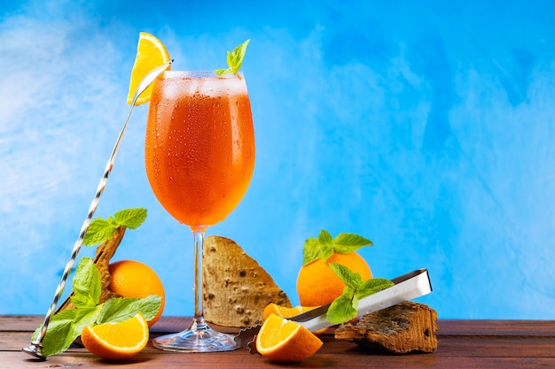 Cocktail aperol spritz e accessori da bar. Cocktail italiano aperol spritz e un'arancia a fette su sfondo blu