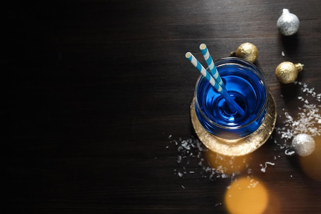 Cocktail blu con cannucce in neve di vetro e palle su sfondo di legno spazio per il testo