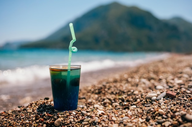 Cocktail blu freddo fresco sulla spiaggia di sabbia tropicale con vista sulle montagne