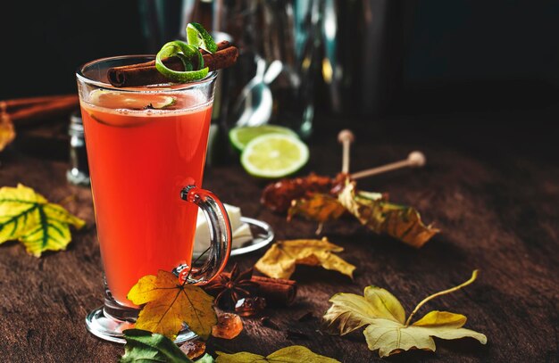 Cocktail caldo di riscaldamento invernale al rum imburrato con succo di mela rum scuro miele cannella in vetro su fondo di legno