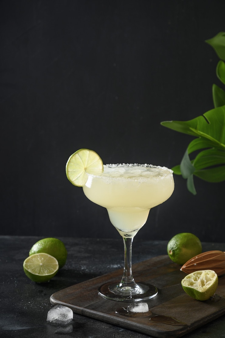 Foto cocktail classico di margarita con succo di lime e cubetto di ghiaccio su sfondo nero con orientamento verticale