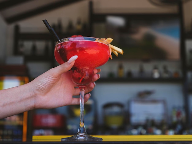 Cocktail colorato nella mano di una ragazza al bar