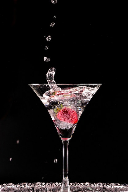 Cocktail con fragole isolato su sfondo nero. Bicchiere di vodka che spruzza.