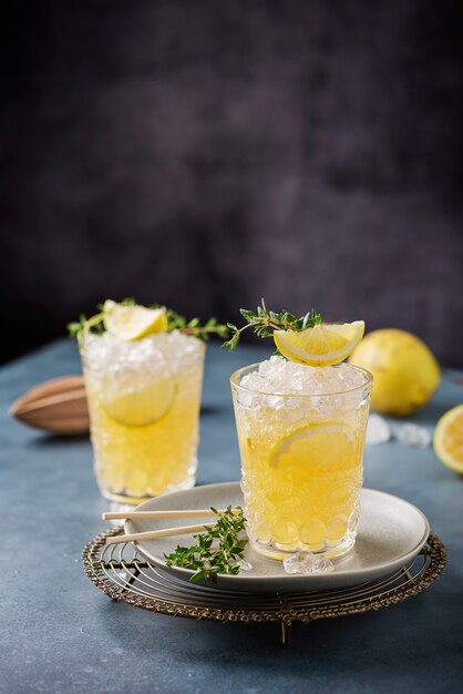 Cocktail con limone, timo e ghiaccio tritato sullo sfondo scuro, concetto di bar e immagine di messa a fuoco selettiva