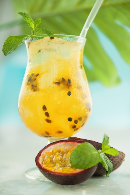 Cocktail con mango e frutto della passione in un bicchiere accanto a metà del frutto della passione