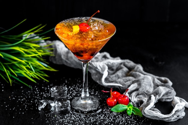 Cocktail dell'arancia dolce con la ciliegia e ghiaccio su fondo nero