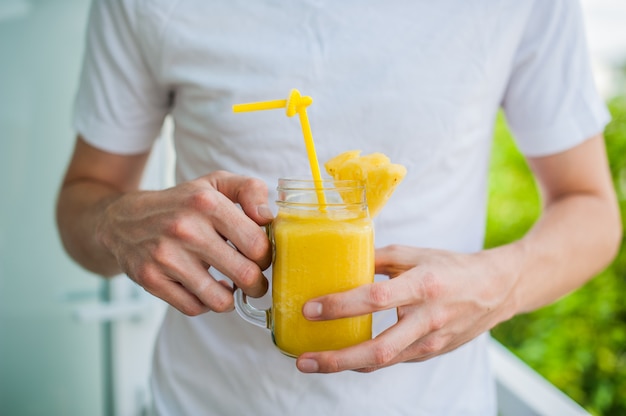 Cocktail di ananas con una fetta di uomo delle mani sulla terrazza. Concetto tropicale