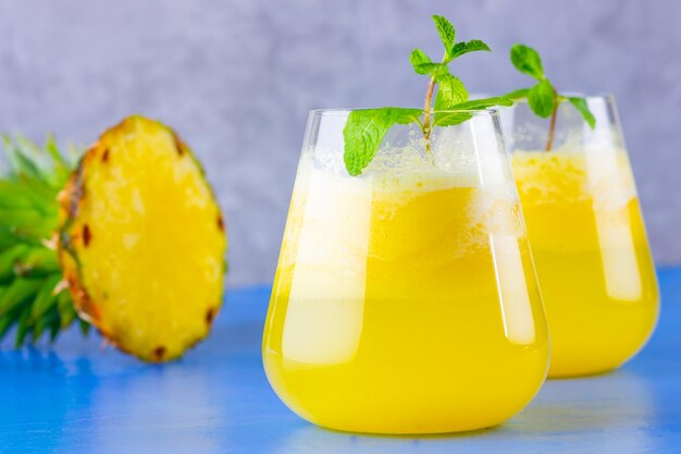 Cocktail di ananas su uno sfondo grigio blu Cocktail freddo di ananas con menta