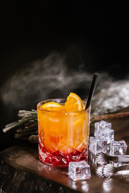 Cocktail di aperol arancione con ghiaccio su sfondo scuro