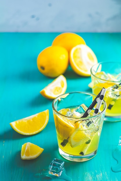 Cocktail di bevanda alcolica al limone con erba di ghiaccio limone e rosmarino su una superficie di sfondo del tavolo in legno turchese blu Limoncello tradizionale italiano fatto in casa con bevanda alcolica al limone