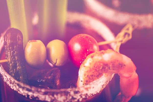 Cocktail di Bloody Mary guarnito con bastoncini di sedano e olive.