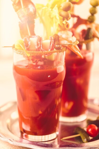 Cocktail di Bloody Mary guarnito con bastoncini di sedano, olive e striscioline di pancetta.