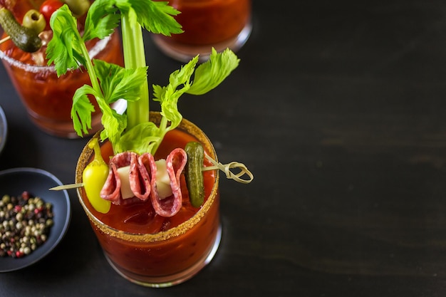 Cocktail di Bloody Mary guarnito con bastoncini di sedano, olive e striscioline di pancetta.