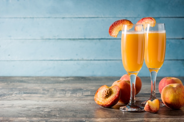 Cocktail di champagne Bellini in cristallo sul tavolo di legno blu