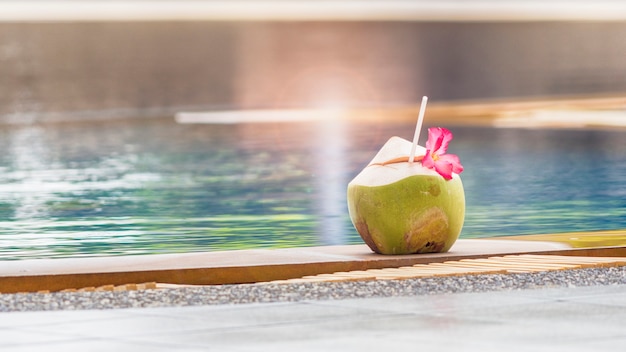 Cocktail di cocco con cannuccia a bordo piscina