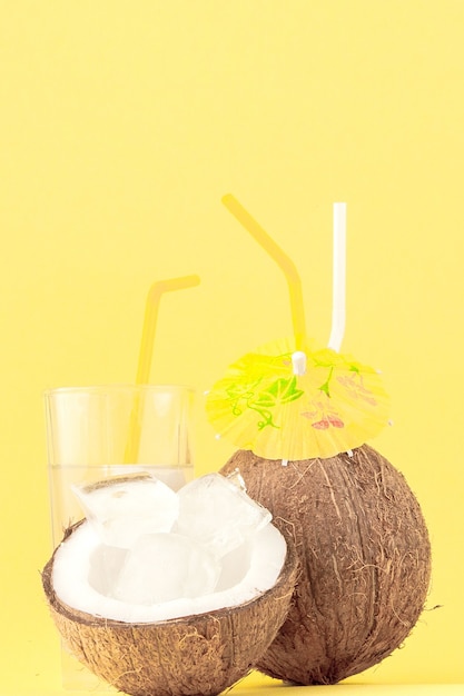 Cocktail di cocco fresco con cannucce su sfondo giallo.