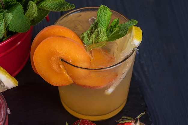 Cocktail di frutta con frutta fresca e ghiaccio. In bicchieri su fondo rustico in legno nero