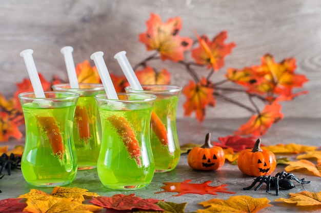 Cocktail di Halloween. Siringhe con sangue in bicchieri con limonata verde, ragni